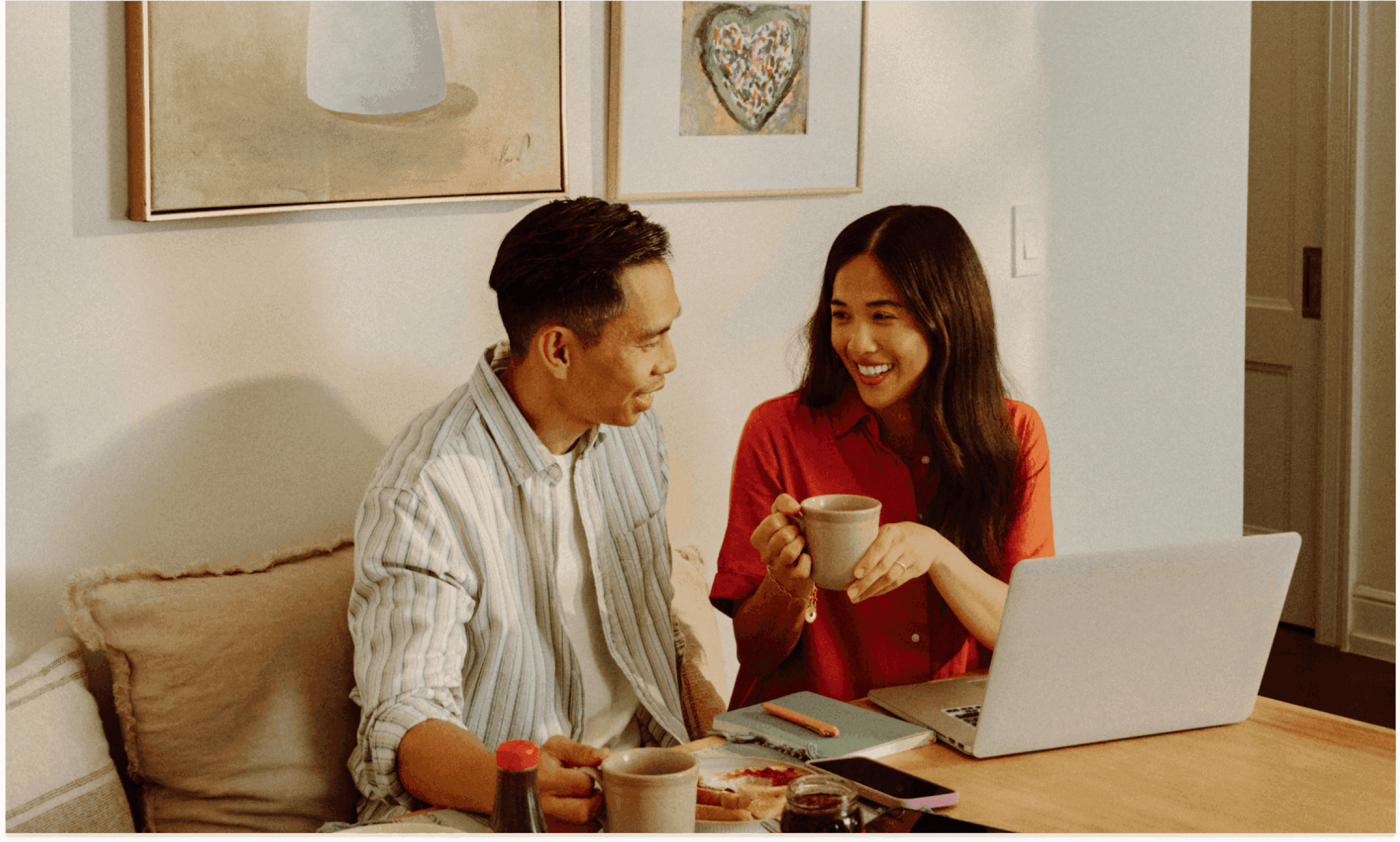 Couple smiling while looking at a laptop at home